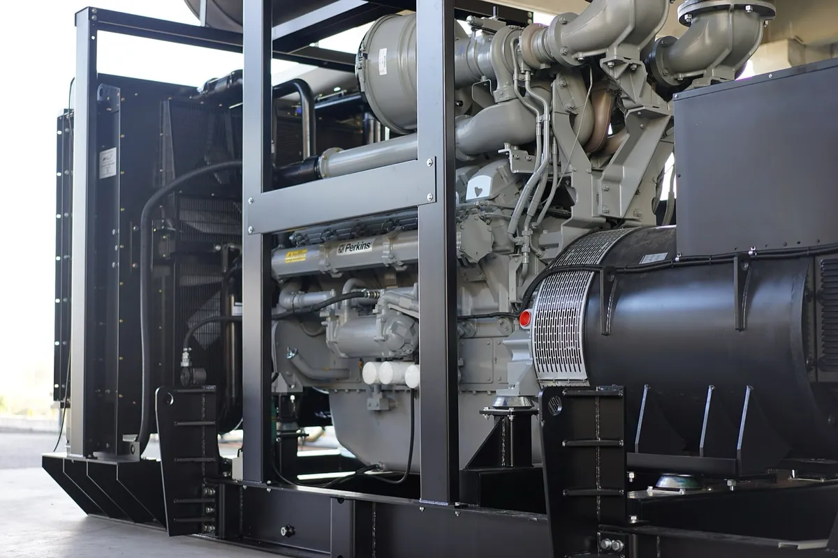 Genset diesel open frame berkapasitas besar dengan mesin, alternator, dan radiator terbuka di atas rangka baja